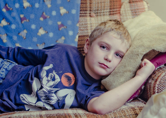 Kind liegt gelangweilt zuhause auf der Couch – Langeweile bei Kindern im Wohnzimmer